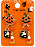 A pair of Halloween-themed dangle earrings on an orange display card. The earrings feature jack-o'-lantern tops with green stems, dangling black shopping bags with white ghosts and gold stars, red beads, and candy corn charms.