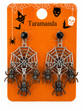 A pair of Halloween spiderweb dangle earrings on an orange retail display card. The earrings feature silver-tone spiderweb frames with black spider charms and black round studs.