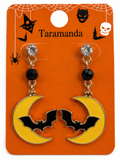 A pair of Halloween-themed dangle earrings on an orange retail display card. Each earring has a clear rhinestone, a black faceted bead, and a yellow crescent moon with a black bat silhouette.