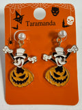 A pair of Taramanda Halloween dangling earrings on an orange display card. The earrings feature a pumpkin jack-o'-lantern with a white top hat, white pearl-like studs, and gold-tone metal.