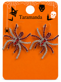 A pair of Halloween spider earrings on a branded orange card. The earrings have silver rhinestone-embellished bodies with dark red rhinestone legs and a red center stone.